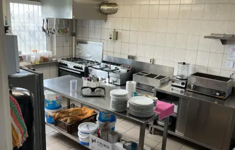A fully equipped canteen kitchen in Gewerbegebiet Altlandsberg shows stainless steel counters, tiled walls, gas stoves and stacked plates.