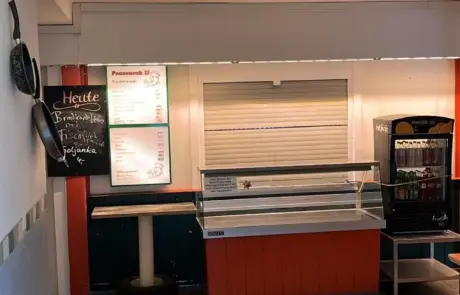Im Gewerbegebiet Altlandsberg zeigt die Kantine einen Verkaufstresen, Tagesmenü-Tafeln und einen Getränkeautomaten in einem einfachen Gastraum.